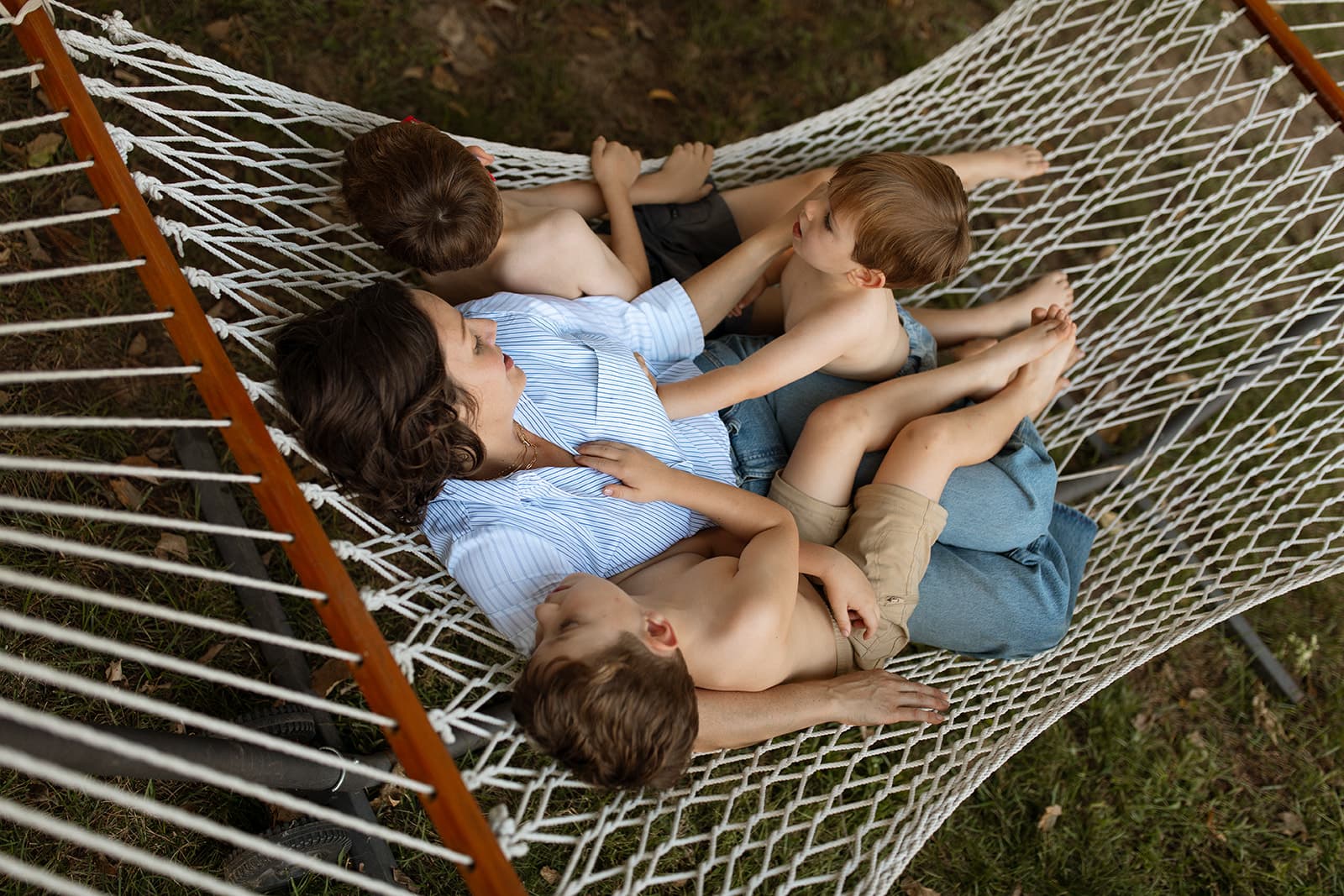 Hannah resting in a hammock outdoors with her three sons