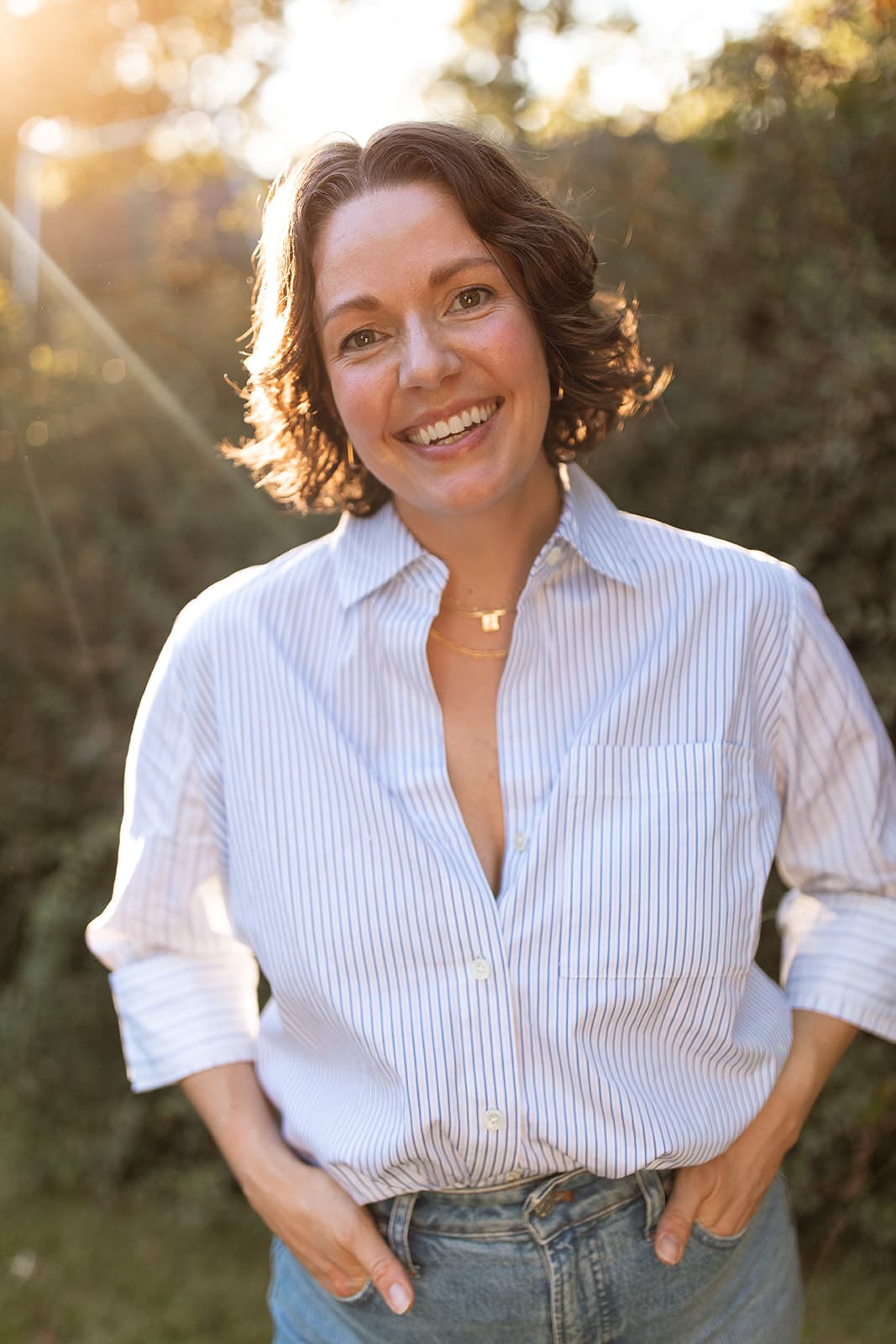 Hannah, a doula, smiling warmly outdoors in golden evening light
