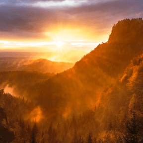 Golden sunlight breaking over misty mountains at dusk