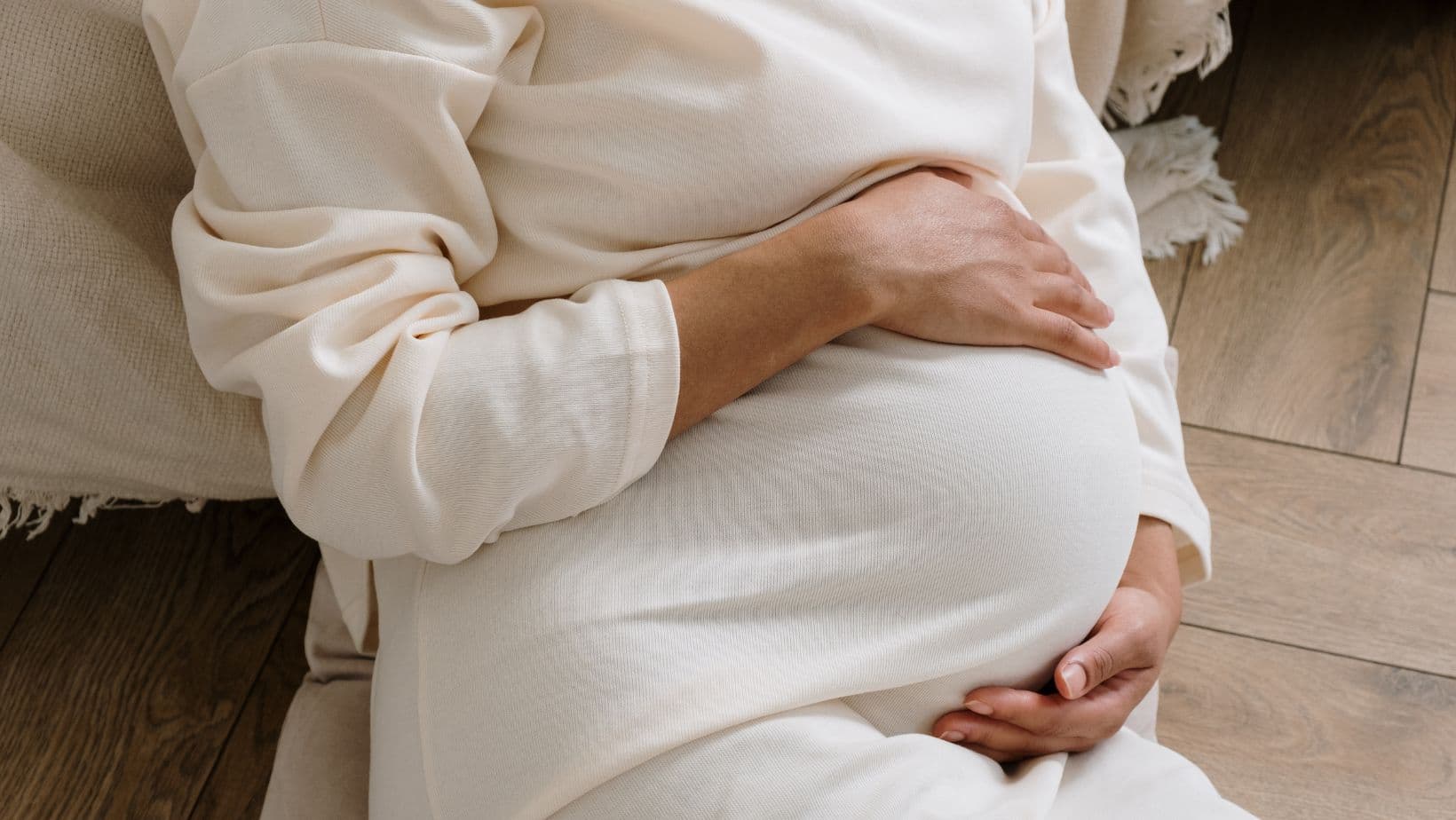 An expectant mother cradling her pregnant belly in soft light