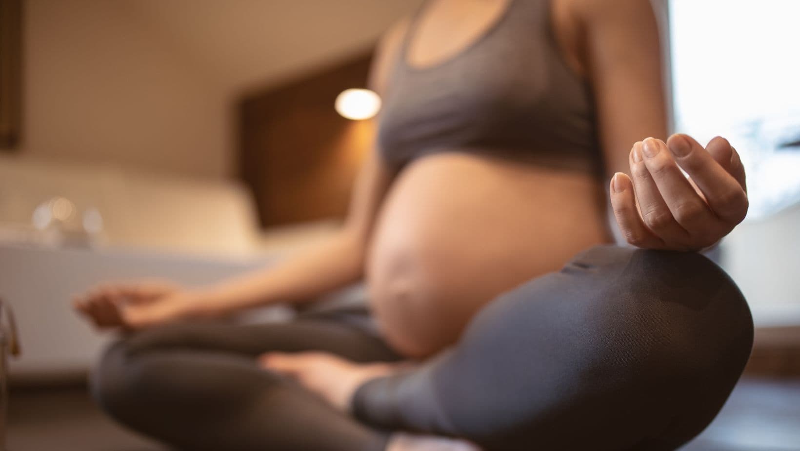 A pregnant woman sitting in quiet meditation in natural light