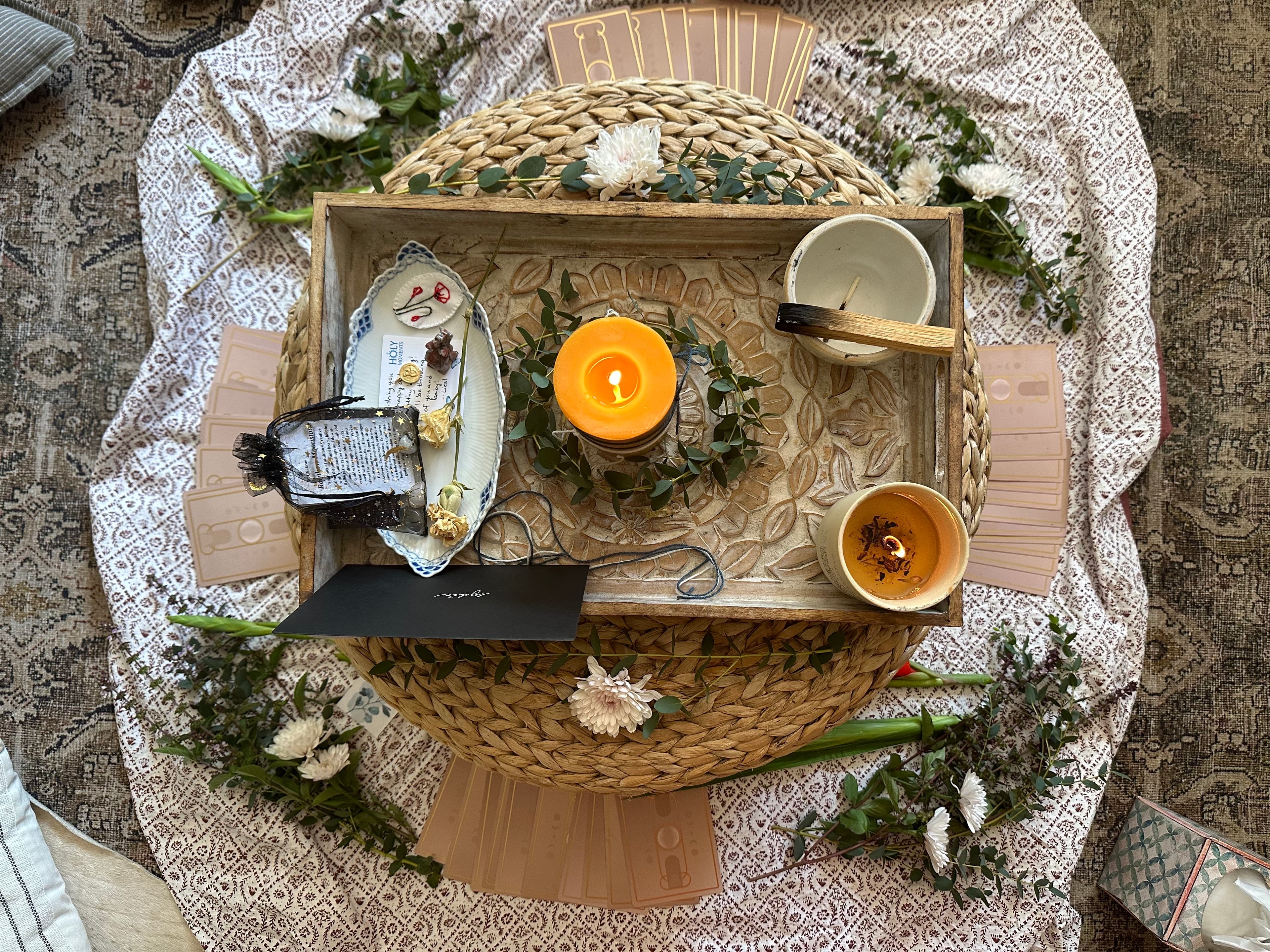 A softly styled ritual tray with candles and botanicals